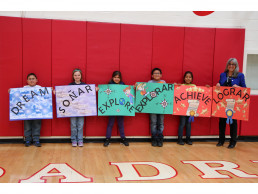 Photo of Students & Dr. Gallegos holding signs that read in English & Spanish - Dream, Explore, Achieve