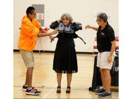 Photo of Dr. Gallegos putting on football shoulder pads during a rally
